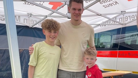 Matthias Ginter steht zwischen zwei jungen Fußballfans, die ihm eben um ein Autogramm gebeten haben