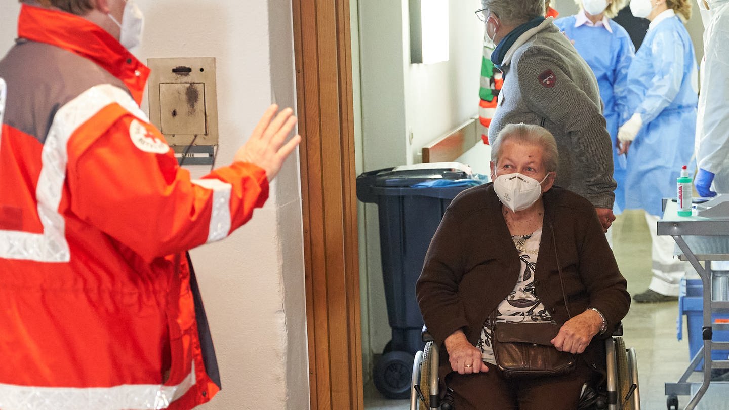 Die 91-jährige Lieselotte Ziegler wird im Altenheim Maria vom Siege im Koblenzer Stadtteil Wallersheim mit ihrem Rollstuhl zur Corona-Impfung gebracht. Die Seniorin ist die erste Rheinland-Pfälzerin, die den Impfstoff erhält.
