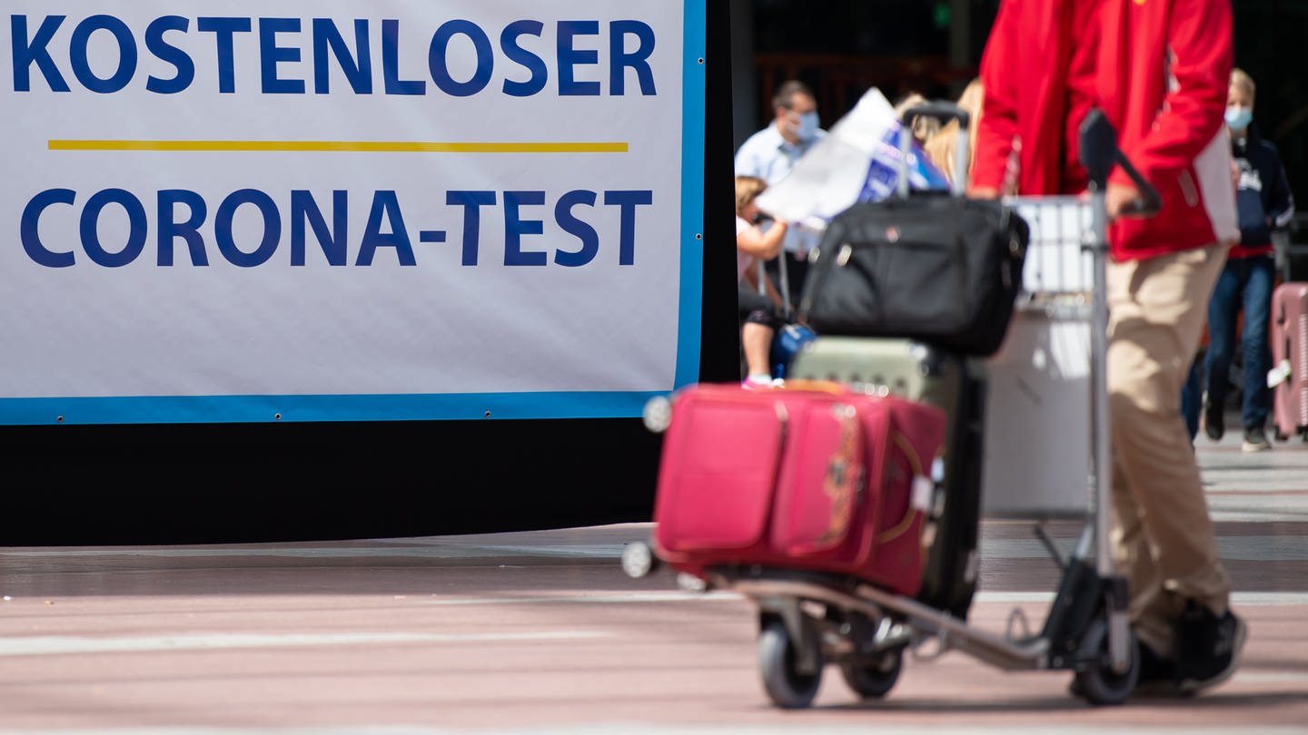 Flugpassagiere gehen am Flughafen Freising an einem Schild mit der Aufschrift 