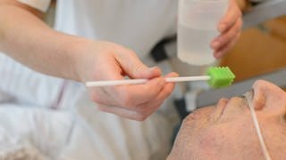 Befeuchten und Reinigung des Mundes eines schwerstkranken Patienten auf einer Palliativstation in einem deutschen Krankenhaus