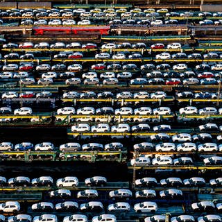 Autozüge mit vielen Neuwagen stehen auf einem Rangierbahnhof 