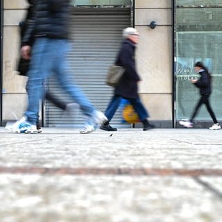 Passanten gehen  an einem leerstehenden Geschäft vorbei 