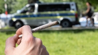 Ein Mensch hält einen Joint in der Hand. Wer sich nicht an die Vorschriften des Cannabisgesetzes hält, muss in RLP künftig hohe Bußgelder zahlen.