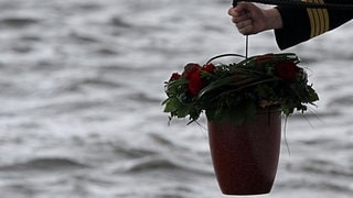 Die Hand eines Kapitäns lässt eine Urne zu Wasser. Das soll künftig in den rheinland-pfälzischen Flüssen möglich sein. Eine entsprechende Gesetzesnovelle wurde nun gebilligt.