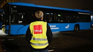 Eine Streikende steht bei einem Warnstreik der Gewerkschaft ver.di am 6. November auf dem Gelände der SWEG (Südwestdeutsche Landesverkehrs-GmbH) vor einem Bus. Der aktuelle Warnstreik im ÖPNV soll bis Mittwoch andauern.