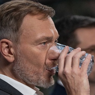 Christian Lindner trinkt Wasser aus einem Glas. Im Hintergrund spricht Marco Buschmann