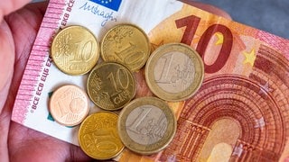 Geldscheine und Euromünzen mit dem Wert von 12,41 Euro liegen auf einer Hand. 