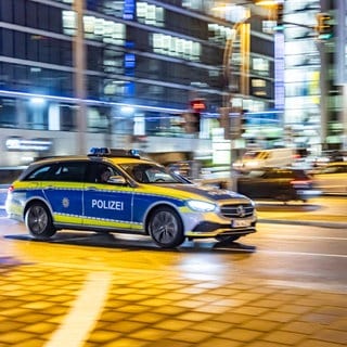 Ein Polizeiauto rast nachts mit Blaulicht durch die Stuttgarter Innenstadt