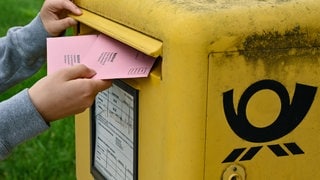 Person wirft Wahlbrief in Briefkasten der Deutschen Post. Am 23. Februar 2025 steht die Bundestagswahl an. Wer seine Stimme per Briefwahl abgeben will, muss sich rechtzeitig um die Unterlagen kümmern. 