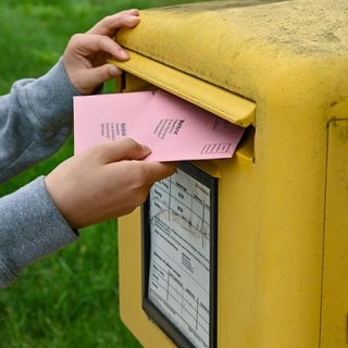 Person wirft Wahlbrief in Briefkasten der Deutschen Post. Am 23. Februar 2025 steht die Bundestagswahl an. Wer seine Stimme per Briefwahl abgeben will, muss sich rechtzeitig um die Unterlagen kümmern. 