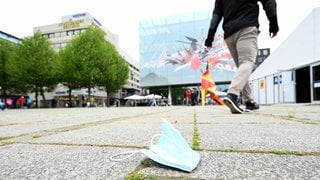 A face mask lies on Schlossplatz while a passer-by walks in the background.  (Photo: dpa Bildfunk, picture alliance/dpa | Bernd Weissbrod)