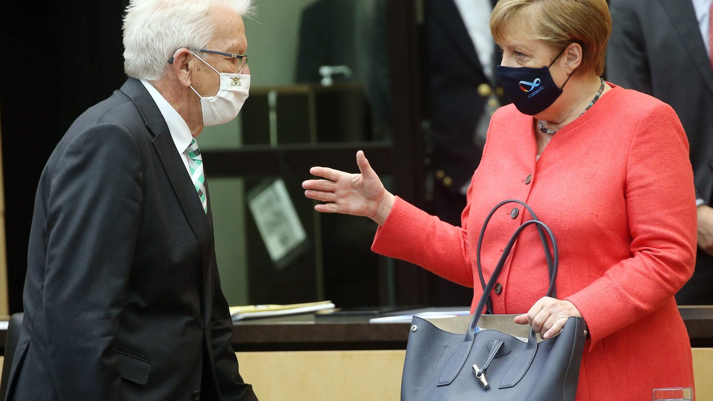 Berlin: Mit Mund- und Nasenschutzmasken unterhalten sich Bundeskanzlerin Angela Merkel (CDU) und Winfried Kretschmann (Bündnis90/Grüne), Ministerpräsident in Baden-Württemberg, zu Beginn der Sitzung im Bundesrat.