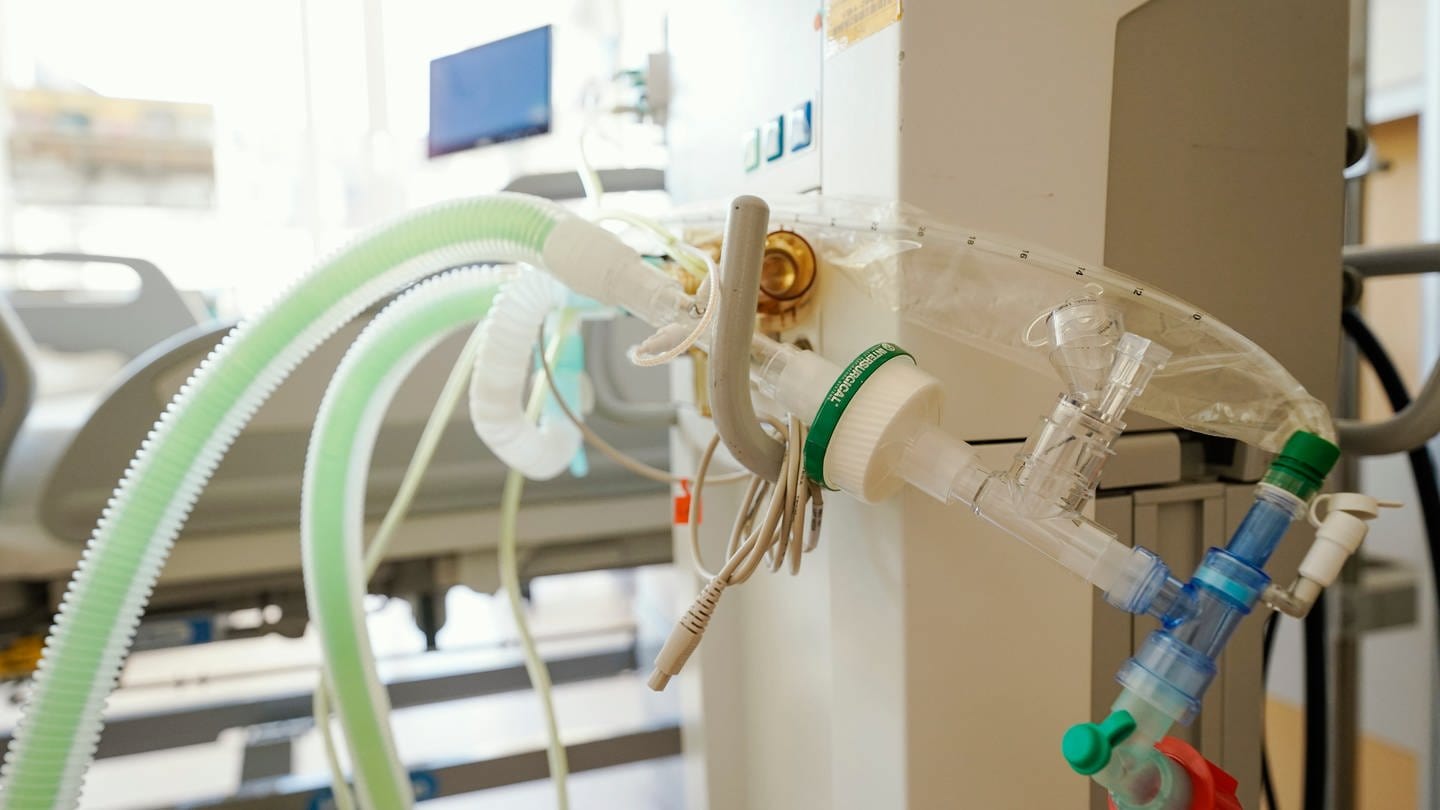 Ein Beatmungsgerät steht vor einem Bett in einem Patientenzimmer auf der Intensivstation einer Klinik.