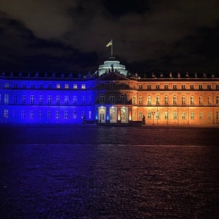 Das Neue Schloss am Schlossplatz in Stuttgart leuchtet in blau-gelben Farben.