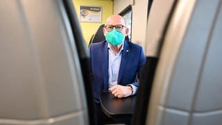 Winfried Hermann (Grünen), der Verkehrsminister von Baden-Württemberg, sitzt in einem Regionalzug und trägt eine FFP2-Maske. 