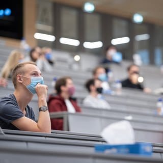 Studierende mit Mund- und Nasenmaske sitzen in einem Hörsaal der Universität Hohenheim in Baden-Württemberg.