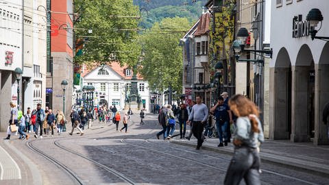 Passanten gehen durch die Freiburger Innenstadt.