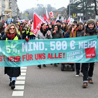 Bei einer Demonstration zum Tarifkonflikt beim öffentlichen Dienst in Karlsruhe nehmen Beschäftigte der Sozial- und Jugendbehörde sowie Beschäftigte des Stadtjugendausschusses Karlsruhe teil. Sie tragen ein Transparent, auf dem steht "10,5 Prozent, mindestens 500 Euro mehr - Ist mehr für uns Alle!". 
