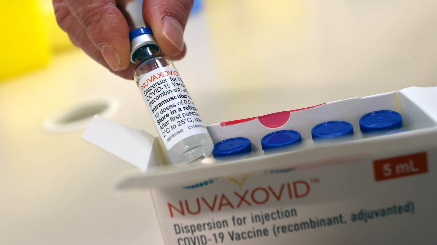 Jemand hält eine Ampulle des soeben ausgelieferten Impfstoffs von Novavax.