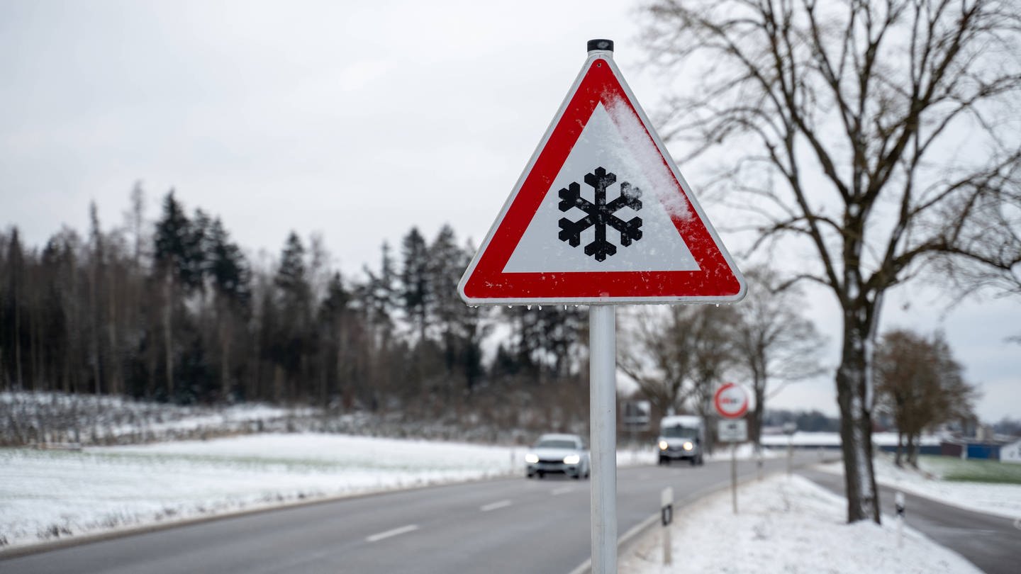 Warnschild vor Schnee und Glätte im Winter auf einer Landstraße