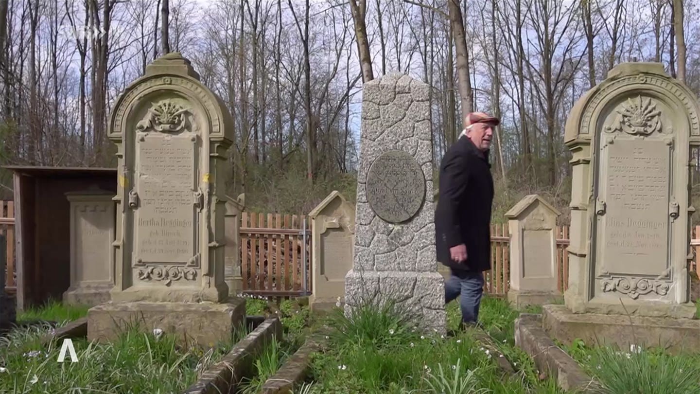 Mann läuft zwischen Grabsteinen auf einem jüdischen Friedhof