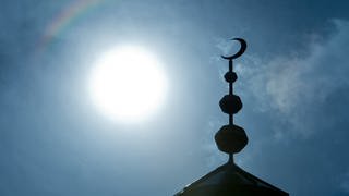 Halbmond auf einer Moschee vor blauem Himmel