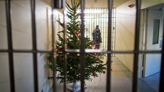 Auf einem mit einem Weihnachtsbaum geschmückten Gefängnisflur schließt ein Justizvollzugsbeamter eine Zellentür ab. Rechtzeitig zu Weihnachten zeigt sich die Justiz in vielen Bundesländern gnädig und entlässt Hunderte Häftlinge vorzeitig aus dem Gefängnis.