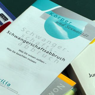 Bücher und Informationshefte zu Schwangerschaftsabbrüchen liegen auf einem Tisch.