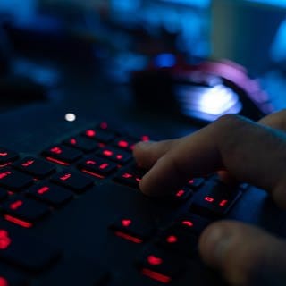 Ein Mann sitzt am Rechner und tippt auf einer Tastatur. 