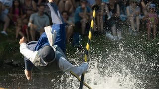Ein Mann in einem historischen Kostüm stürzt beim Ulmer Fischerstechen in die Donau. Bei dem traditionellen Wettkampf versuchen Kontrahenten, sich gegenseitig mit Lanzen aus Booten zu stoßen.