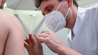 Ein Arzt impft am Klinikum Stuttgart einen Mann in einer Impftstaion in Stuttgart gegen das Coronavirus.