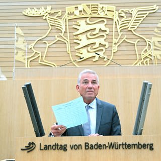 BW-Innenminister Thomas Strobl (CDU) steht am Pult im Landtag vor dem Untersuchungsausschuss, im Hintergrund das BW-Wappen.