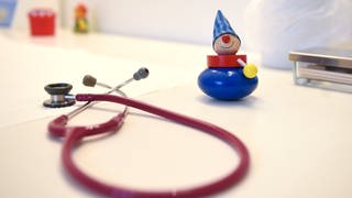 Ein Stethoskop und Kinderspielzeug liegen in einer Kinderarztpraxis.