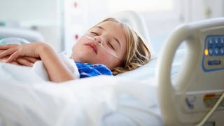 Ein Kind liegt in einem Bett in einer Kinderklinik.