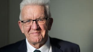 Ministerpräsident Winfried Kretschmann (Grüne) lächelt milde in die Kamera. 