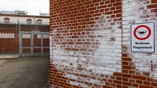 Gefängnismauern der Justizvollzugsanstalt Neumünster mit Hinweisschild für Drohnenflugverbot.