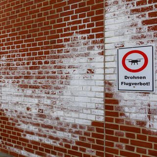 Gefängnismauern der Justizvollzugsanstalt Neumünster mit Hinweisschild für Drohnenflugverbot.