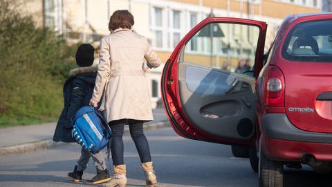 Eine Mutter und ihr Kind gehen in der Nähe einer Schule neben einem Auto, aus dem sie eben ausgestiegen waren (Symbolbild).