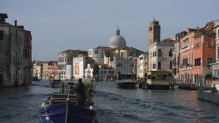 Blick aus einem Vaporetto (Wasserbus) auf den Canale Grande von Venedig: Hinter den Häusern der Stadt ragen die Kuppel der Basilica San Marco und der Glockenturm Campanile auf. 