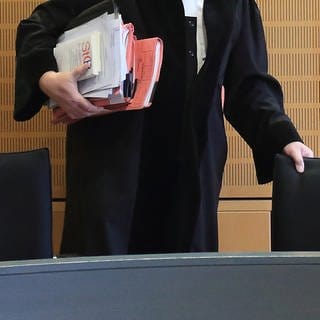 Ein Richter rückt sich in einem Verhandlungssaal seinen Stuhl zurecht.