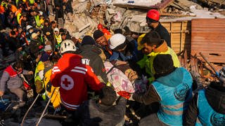 Die 82-jährige Hatice Korkut (M) wird lebend aus einem zerstörten Gebäude gerettet. Unter den Tausenden eingestürzten Gebäuden im türkisch-syrischen Grenzgebiet sind vermutlich noch Zehntausende Erdbebenopfer zu befürchten. (Aufgenommen am 9.2.)