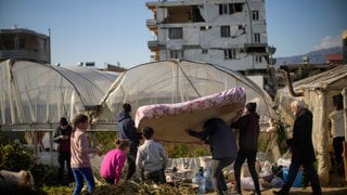 Anwohner bringen eine Matratze in ein Gewächshaus, in dem sie nach dem Erdbeben Schutz suchen. Auch rund eineinhalb Wochen nach der Erdbebenkatastrophe mit Zehntausend Toten erschüttern immer noch weitere Erdstöße die Katastrophenregion.