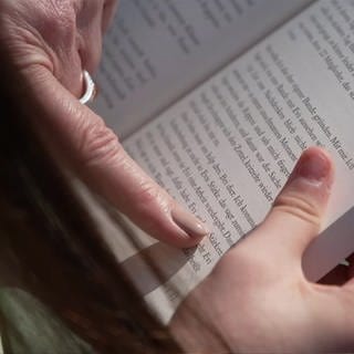 Finger zeigt auf ein Wort in einem Buch