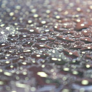 Wassertropfen mit Saharastaub bilden auf einem Autodach ein Muster