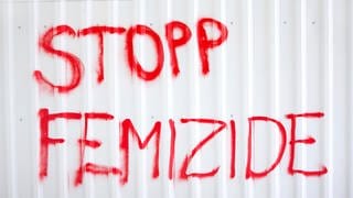 Eine Wellblechwand mit der gesprühten Aufschrift "Stopp Femizide"