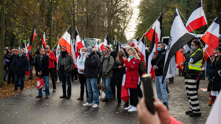 Demonstranten tragen schwarzrotweiße Flaggen.