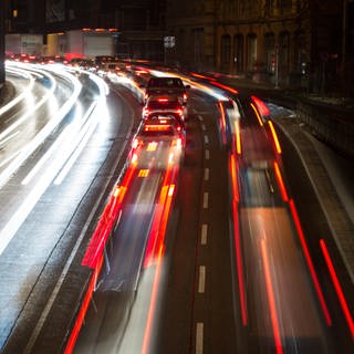 Autos fahren nachts auf einer Straße, die Lichter verschwimmen durch einen Zeitraffer-Effekt.