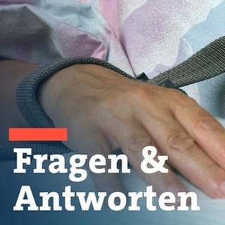 Eine mit einem Textilband festgebundene Hand eines Patienten - die Fixierung bzw. Fixation eines Patienten in der Krankenpflege durch Festschnallen am Handgelenk.