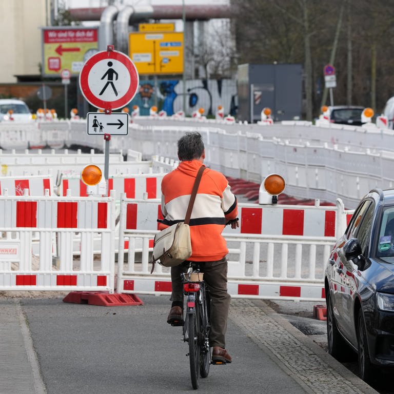 Ein Fahrradfahrer wartet auf dem vor einer Baustelle endenden Radweg auf den Gegenverkehr.