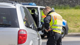 Ein Polizist kontrolliert ein Fahrzeug auf einem Rastplatz. 